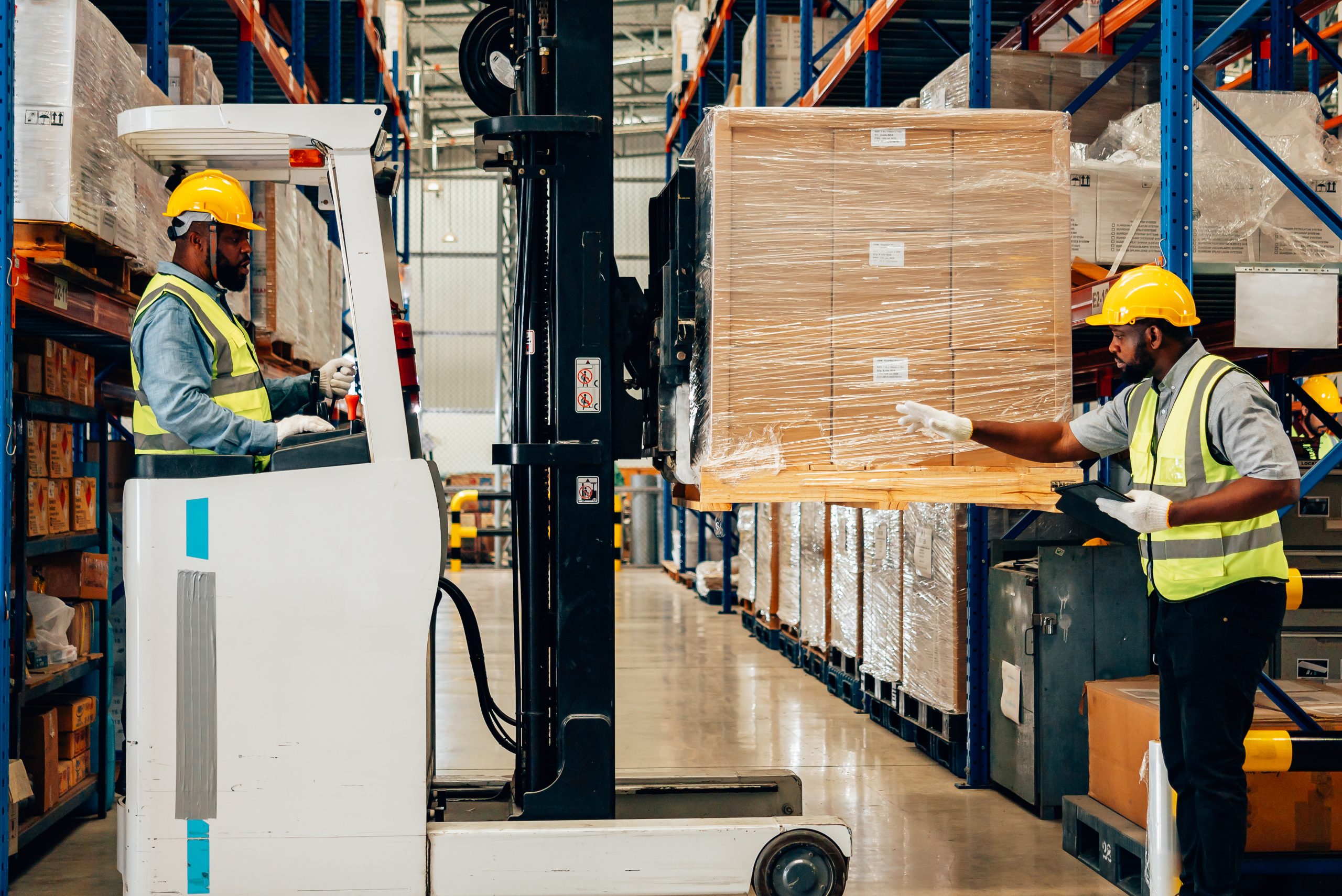 Warehouse worker controlling boxes in warehouse, Professional male warehouse worker moving cardboard boxes by forklift stacker loader, Worker driving cart through storage area